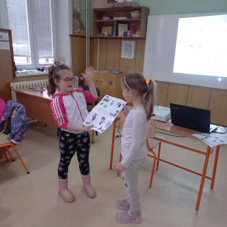 2 girls presenting a poster in a classroom