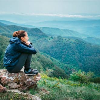 Lonely woman on top of a mountain